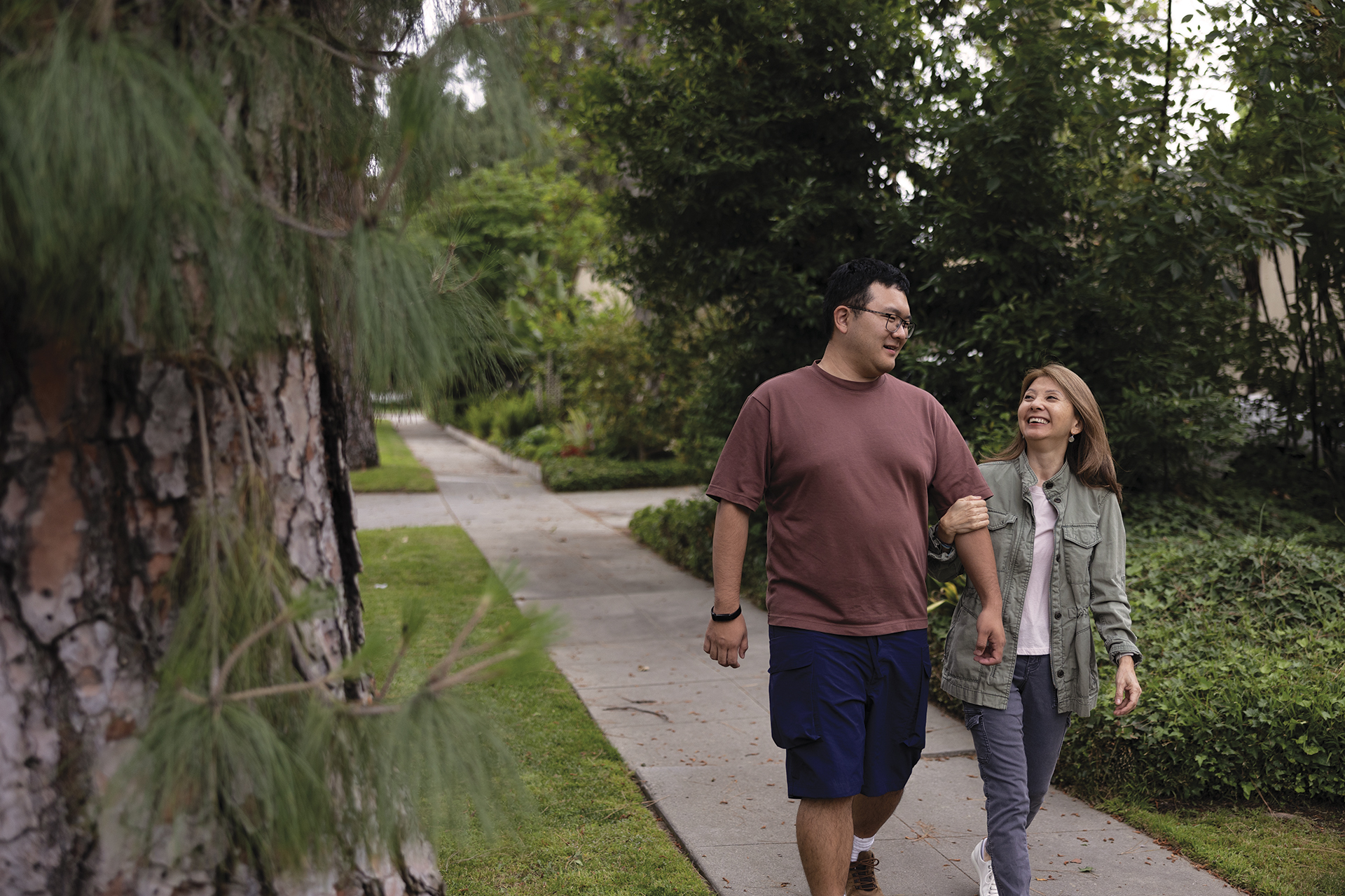 A man walks arm in arm down the sidewalk with a companion.